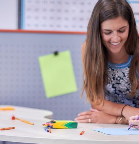 A teacher sitting at a table with her students.