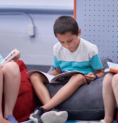 Kids reading books on comfy bean bag chairs.