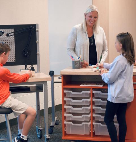Teacher talking with students while they work.