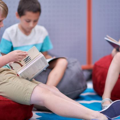 Children sitting on bean bags reading books.