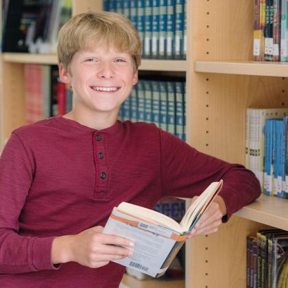 Young boy holding a book in the library.