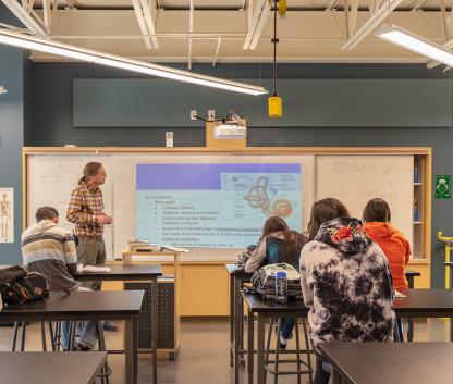 A science teacher lecturing in front of a built-in learning wall.