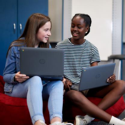 Two middle school students working on a laptop together.
