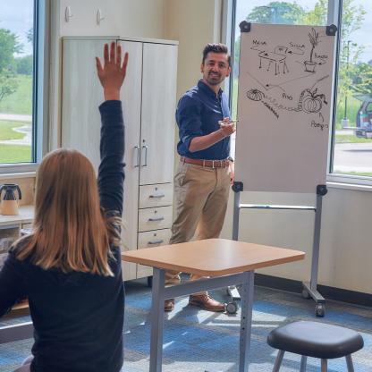 Teacher standing next to whiteboard.