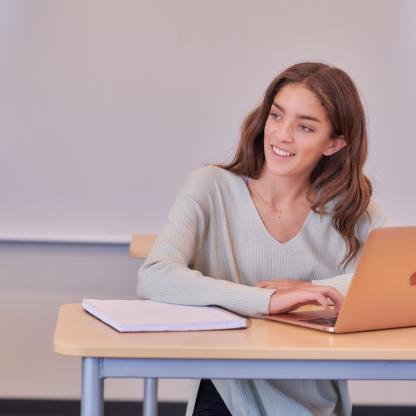 Teenage girl sitting at table with laptop.