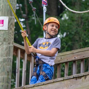 A young boy smiling as he starts to zipline.