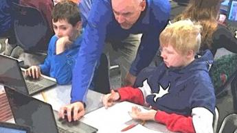 Teacher crouching down to help a student